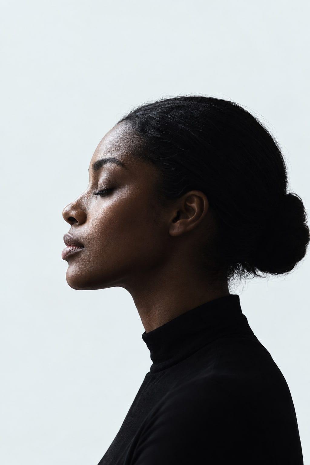 A woman’s profile, eyes closed in thought, in cool grey light